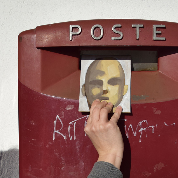 Una mano mette il ritratto di un uomo fatto su una cartolina nella cassetta della posta
