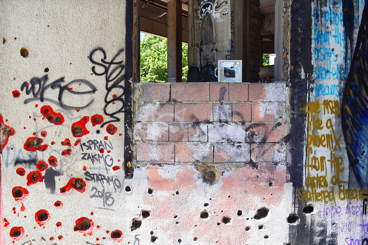dono d'arte abbandonato su un muro con street art e buchi da sparo
