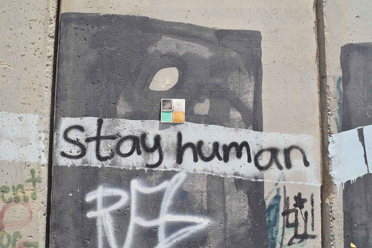 un graffito sul muro Israele Palestina con la scritta "stay human" con un dono d'arte abbandonato sopra